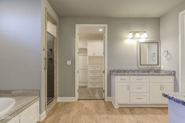136 Preston Hollow Ln, Wolfforth, TX 79382 - full bath featuring a stall shower, vanity, wood finished floors, a walk in closet, and a bath