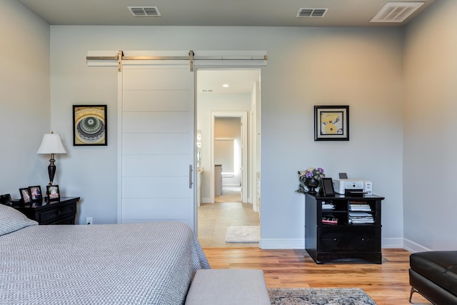 bedroom featuring a barn door and light wood-type flooring