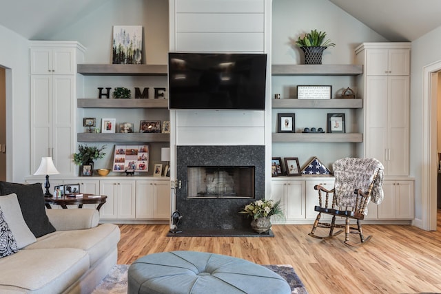 living room featuring vaulted ceiling, built in features, and light wood-type flooring