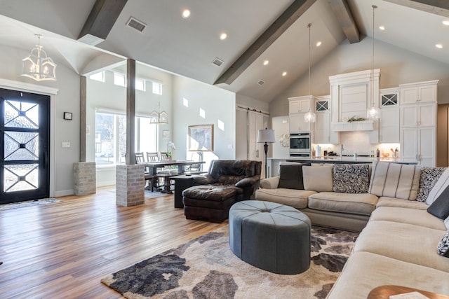 living room with an inviting chandelier, high vaulted ceiling, light hardwood / wood-style flooring, and beamed ceiling