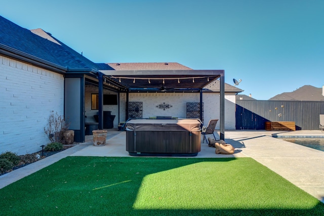 rear view of house featuring ceiling fan, a hot tub, a patio area, and a lawn