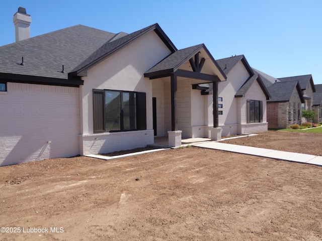 4622 140th St, Lubbock, TX 79423 - view of front of house featuring brick siding, a shingled roof, and a chimney