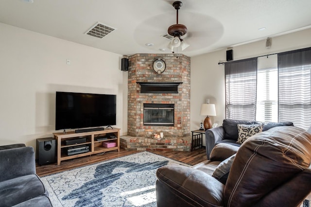 living room featuring ceiling fan, dark hardwood / wood-style floors, and a fireplace