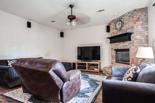 living room with hardwood / wood-style flooring, a brick fireplace, and ceiling fan