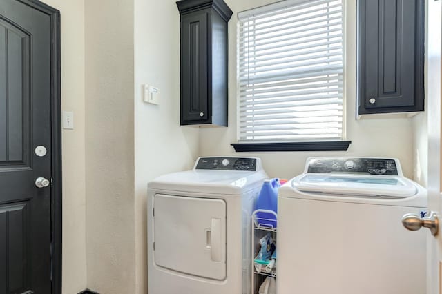 clothes washing area with cabinets and washer and clothes dryer