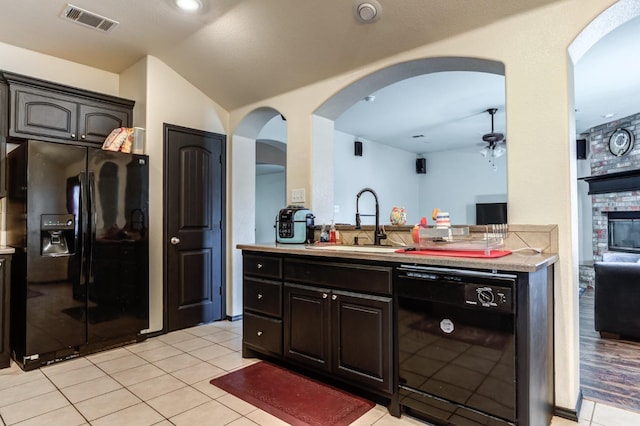 kitchen with sink, a fireplace, black appliances, and light tile patterned flooring