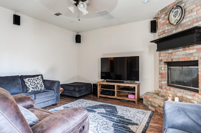 living room featuring ceiling fan, dark hardwood / wood-style flooring, and a brick fireplace