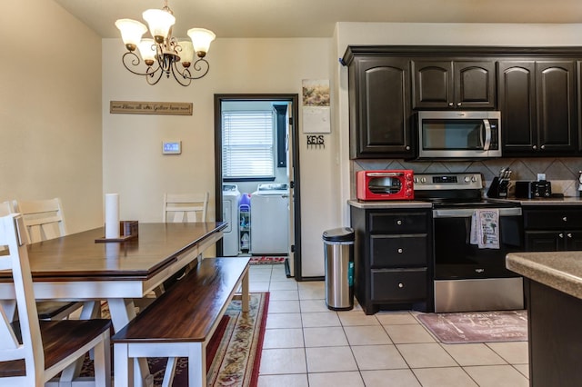 kitchen featuring light tile patterned floors, appliances with stainless steel finishes, backsplash, washer and dryer, and a chandelier