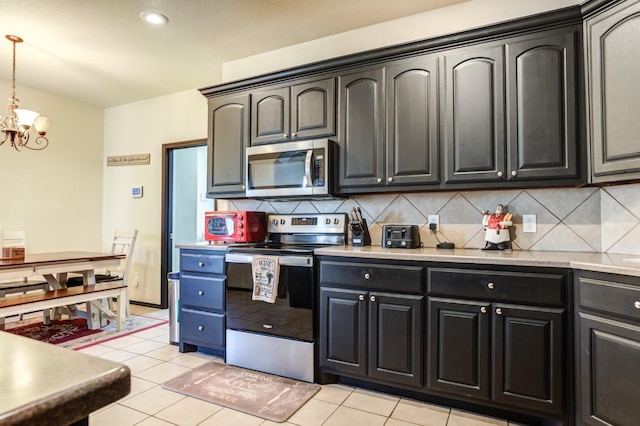 kitchen featuring stainless steel appliances, tasteful backsplash, light tile patterned floors, and an inviting chandelier