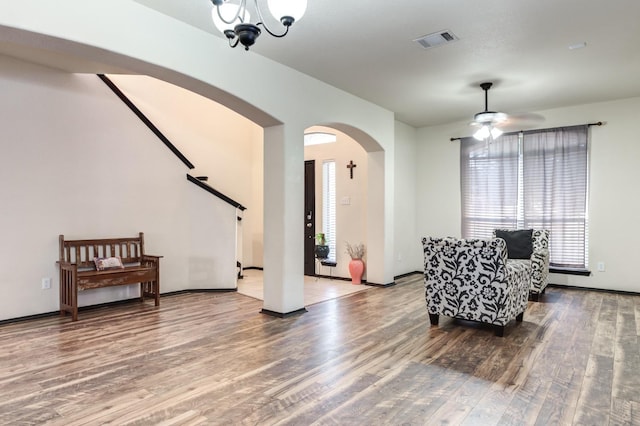 living area featuring hardwood / wood-style flooring and ceiling fan with notable chandelier