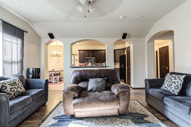 living room with lofted ceiling, ceiling fan with notable chandelier, and light wood-type flooring