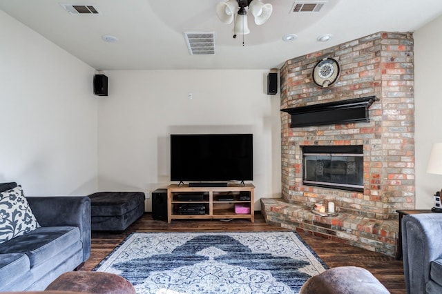 living room with ceiling fan, dark hardwood / wood-style floors, and a brick fireplace