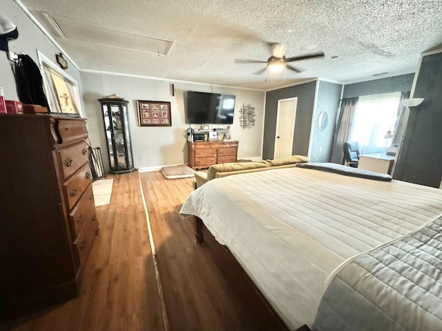 bedroom featuring ornamental molding, hardwood / wood-style floors, a textured ceiling, and ceiling fan