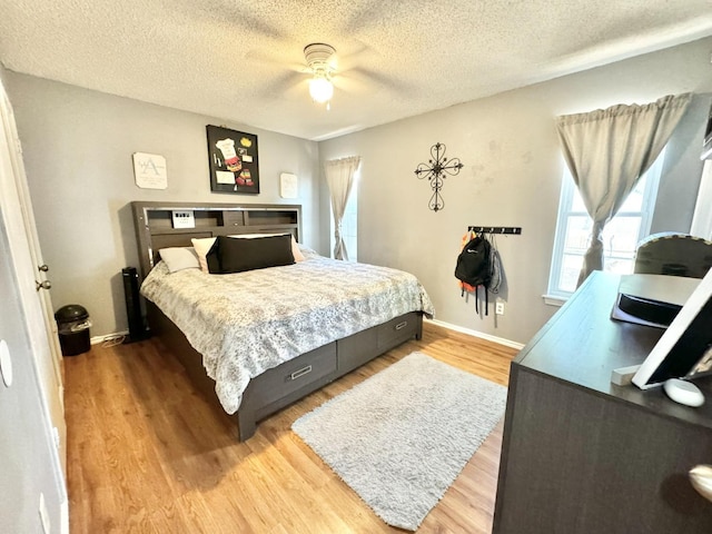 bedroom with ceiling fan, wood-type flooring, and a textured ceiling