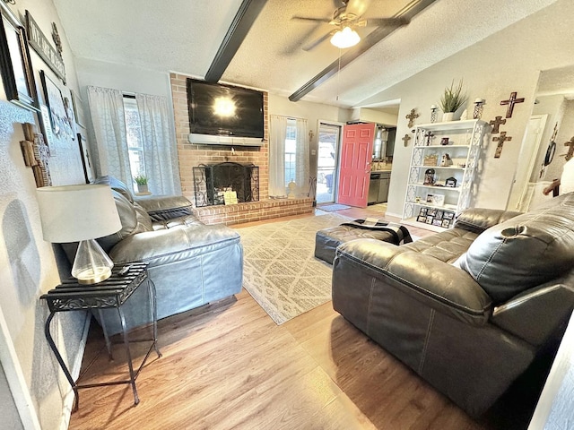 living room featuring hardwood / wood-style floors, a fireplace, lofted ceiling with beams, ceiling fan, and a textured ceiling