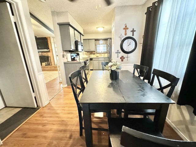 dining area with light hardwood / wood-style floors and a textured ceiling