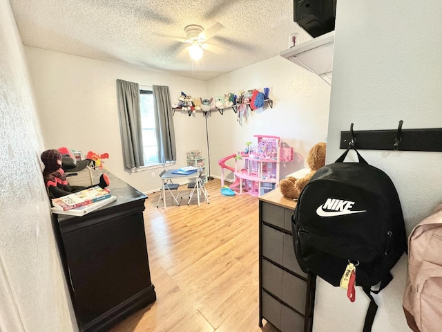 playroom featuring ceiling fan, hardwood / wood-style floors, and a textured ceiling