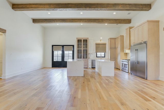 kitchen with premium appliances, french doors, light wood finished floors, open floor plan, and a kitchen island