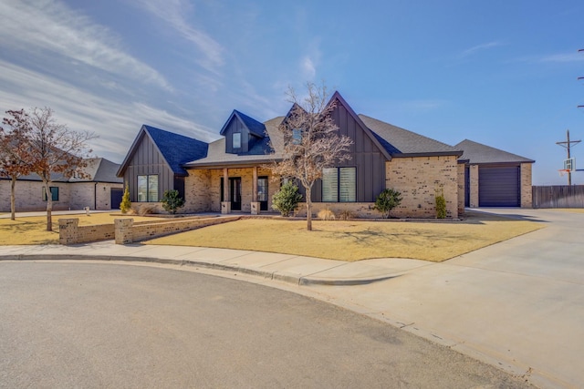 view of front of house with driveway, brick siding, and board and batten siding