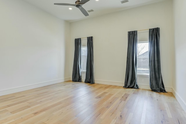 spare room featuring ceiling fan, light wood-style flooring, visible vents, and baseboards