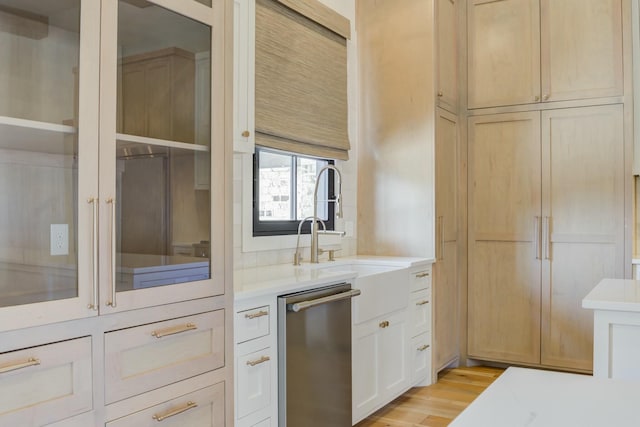 kitchen with light wood-type flooring, light countertops, dishwasher, and a sink