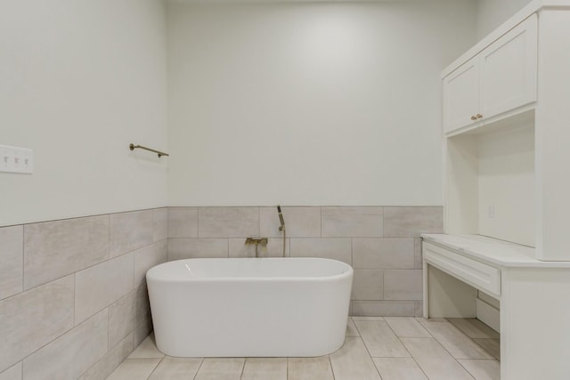 full bathroom with a wainscoted wall, a soaking tub, tile walls, and tile patterned floors