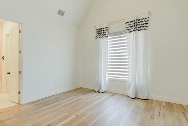 unfurnished room with vaulted ceiling, light wood-style flooring, visible vents, and baseboards