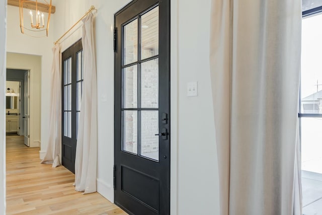 foyer entrance with a wealth of natural light, light wood finished floors, and an inviting chandelier