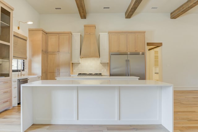 kitchen featuring appliances with stainless steel finishes, a center island, light countertops, and custom exhaust hood