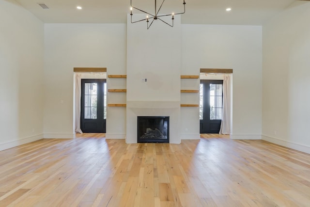 unfurnished living room with a wealth of natural light, a high ceiling, visible vents, and light wood-style floors