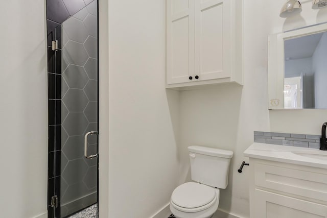 bathroom featuring a stall shower, baseboards, vanity, and toilet