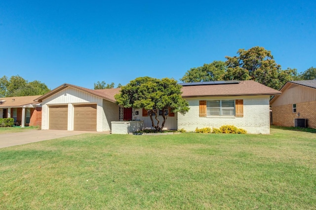 ranch-style house featuring central AC unit, a garage, a front lawn, and solar panels