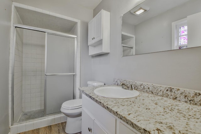 bathroom featuring hardwood / wood-style flooring, vanity, toilet, and a shower with shower door