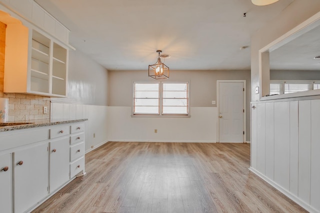 unfurnished dining area featuring sink, a chandelier, and light hardwood / wood-style flooring