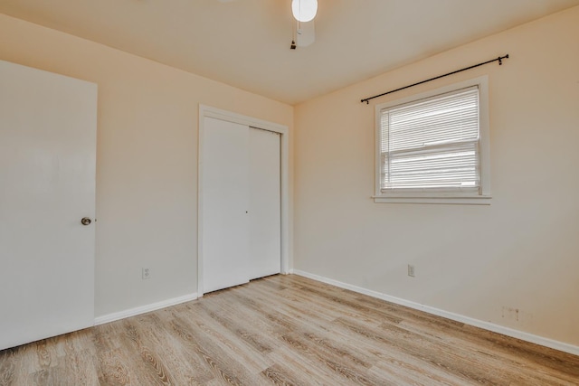 unfurnished bedroom featuring ceiling fan, a closet, and light wood-type flooring