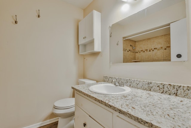 bathroom featuring vanity, tiled shower, and toilet