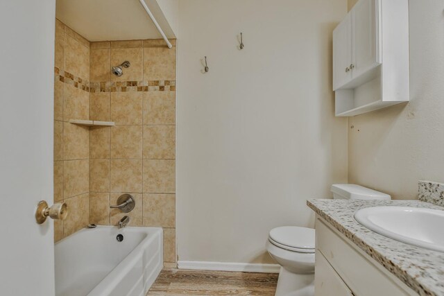 full bathroom with wood-type flooring, toilet, tiled shower / bath combo, and vanity