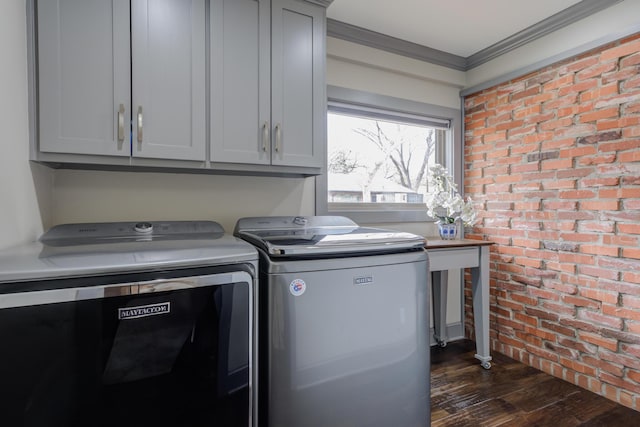laundry room with dark wood-style floors, cabinet space, brick wall, washing machine and dryer, and crown molding