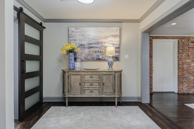 hall with dark wood-type flooring, a barn door, ornamental molding, and baseboards