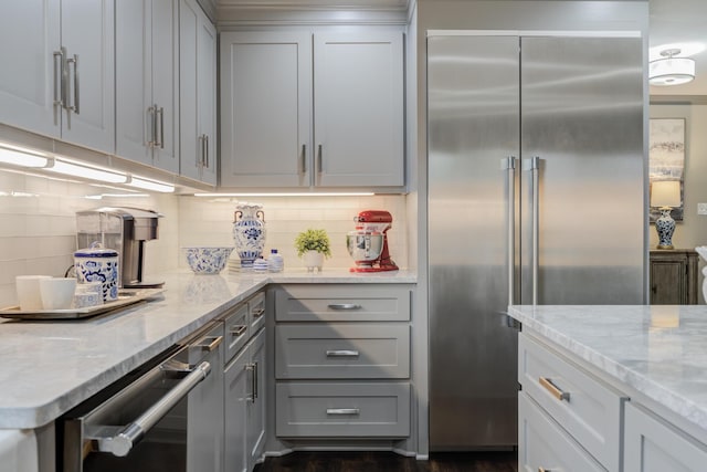 kitchen featuring gray cabinets, stainless steel built in refrigerator, light stone countertops, and decorative backsplash