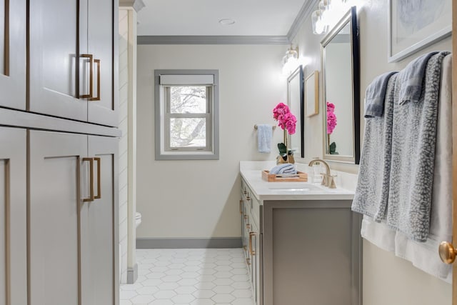 bathroom with ornamental molding, toilet, vanity, and baseboards