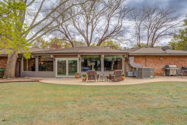 back of house with central air condition unit, a patio, and brick siding