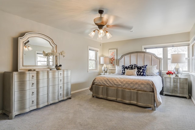 carpeted bedroom featuring ceiling fan, baseboards, and multiple windows