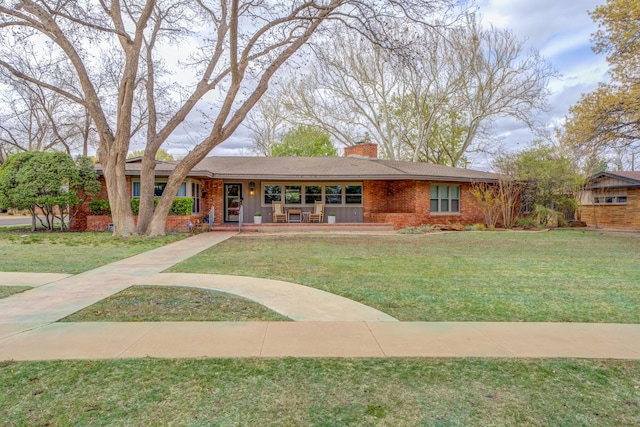 ranch-style home featuring a front lawn, a porch, a chimney, and brick siding