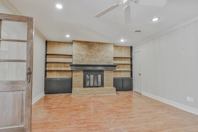 unfurnished living room featuring a fireplace, ornamental molding, light hardwood / wood-style floors, and ceiling fan