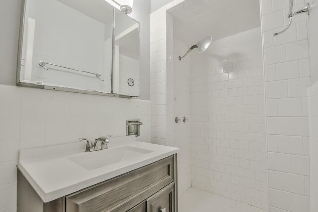 bathroom featuring a tile shower, vanity, and tile walls