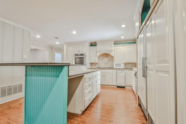 kitchen with tasteful backsplash, crown molding, oven, and white cabinets