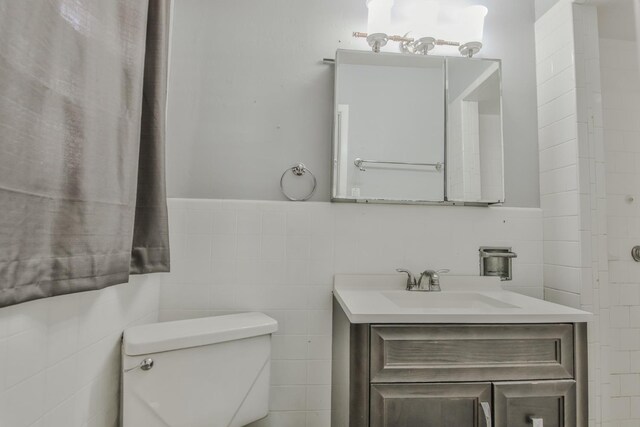 bathroom with vanity, tile walls, and toilet