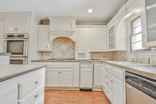 kitchen with sink, light hardwood / wood-style flooring, appliances with stainless steel finishes, tasteful backsplash, and white cabinets