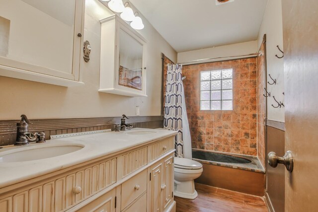 full bathroom with shower / tub combo with curtain, wood-type flooring, toilet, and vanity